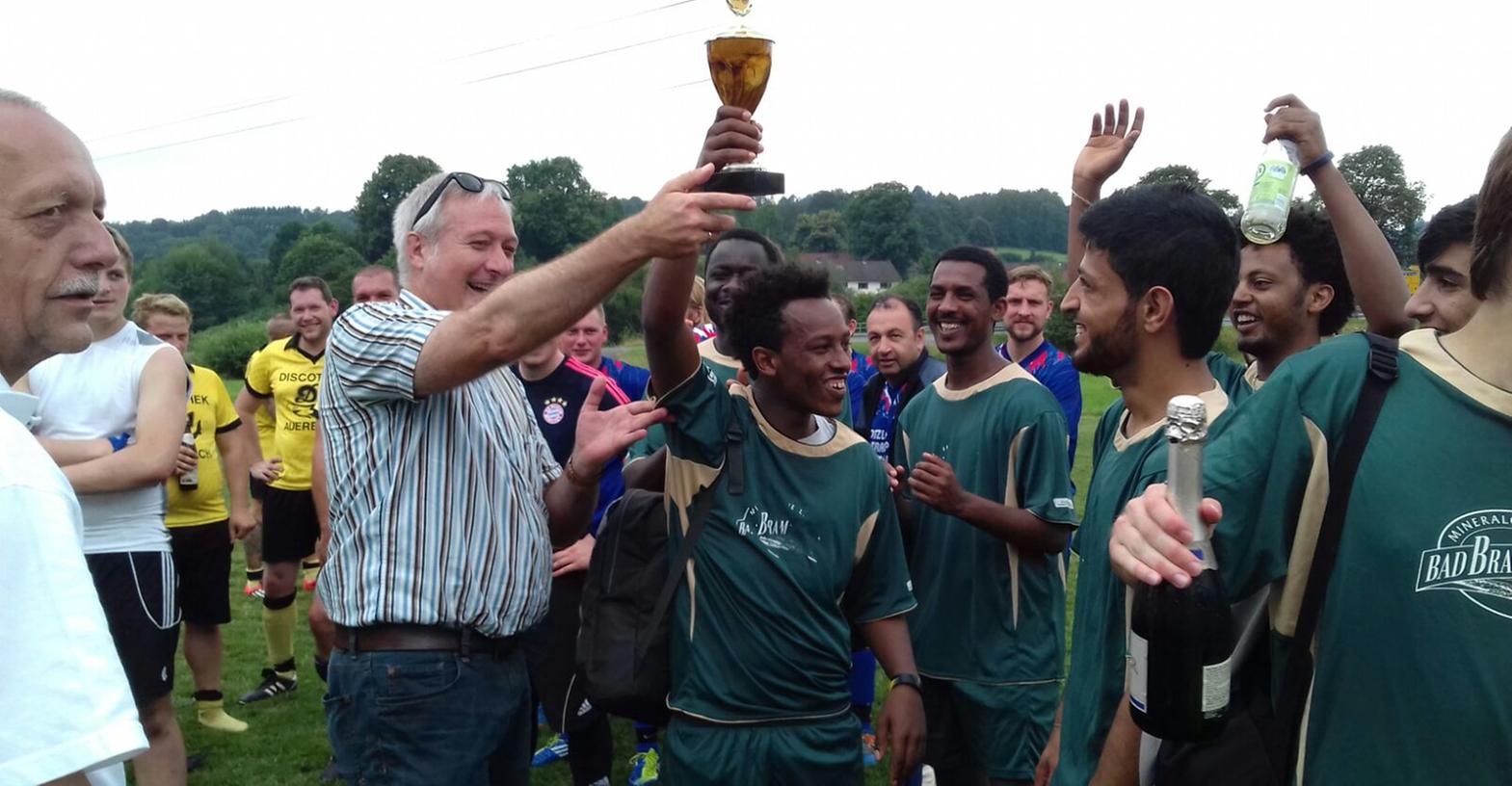 Die Flüchtlingsmannschaft aus Pegnitz beteiligte sich beim Dorffest in Buchau am Fußballturnier. Bürgermeister Uwe Raab (gstreiftes Hemd)überreichte den Pokal.