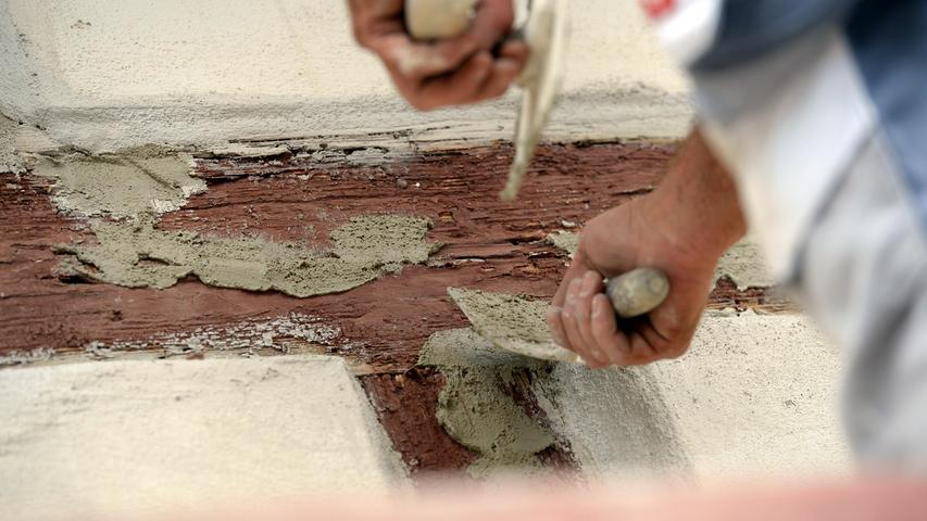 Nachdem die Handwerker die Wände mit einem Dampfstrahler gereinigt haben, entfernen sie die alte Farbe so gut wie möglich und befestigen die Fachwerkfelder neu.