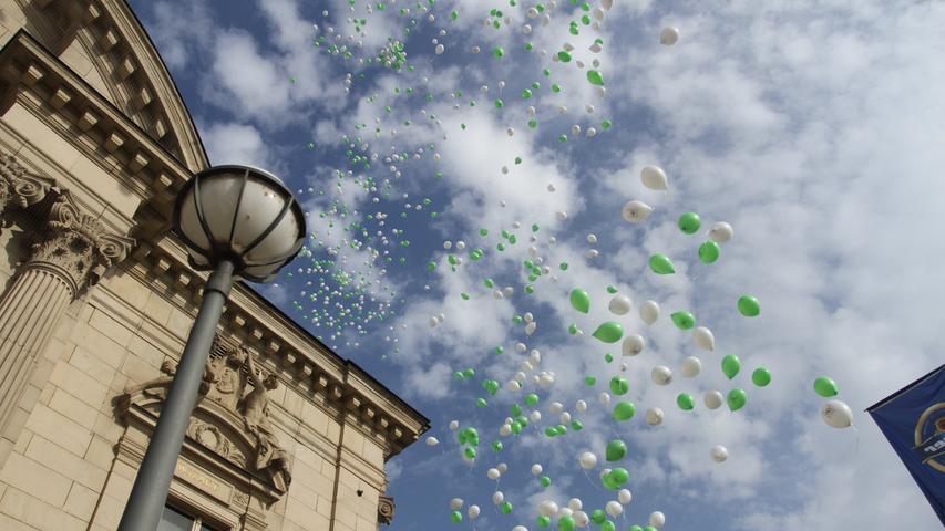 Weiße und grüne Ballons steigen zum Start der Michaelis-Kirchweih vom Stadttheater-Vorplatz in den Fürther Himmel auf.