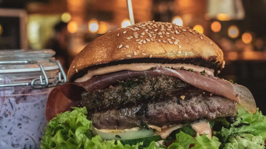 Wem zwei Scheiben Fleisch, Käse und Jalapeños nicht genug auf dem Burger sind, hat die Möglichkeit in der Kuhmuhne noch Shrimps, Ei oder andere Extras obendrauf zu bestellen. Genau nach dem Geschmack eines Kollegen, der sich schon einmal alle Zutaten auf den sogenannten Heart Attack-Burger hat packen lassen, was die Kuhmuhne übrigens dazu veranlasst hat, eine persönliche Botschaft an die Redaktion zu schicken. Fleisch vom Metzger aus der Region, Gemüse aus dem Knoblauchsland und sogar die Brötchen kommen von einem Nürnberger Meisterbäcker - das riecht ja schon nach Franken. Mit 481 Stimmen hat die Kuhmuhne eine ordentliche Fangemeinde hinter sich stehen: Platz 2.
Mehr zur Kuhmuhne gibt es in unserer Gastro-Datenbank. Wem zwei Scheiben Fleisch, Käse und Jalapeños nicht genug auf dem Burger sind, hat die Möglichkeit in der Kuhmuhne noch Shrimps, Ei oder andere Extras obendrauf zu bestellen. Genau nach dem Geschmack eines Kollegen, der sich schon einmal alle Zutaten auf den sogenannten Heart Attack-Burger hat packen lassen, was die Kuhmuhne übrigens dazu veranlasst hat, eine persönliche Botschaft an die Redaktion zu schicken. Fleisch vom Metzger aus der Region, Gemüse aus dem Knoblauchsland und sogar die Brötchen kommen von einem Nürnberger Meisterbäcker - das riecht ja schon nach Franken. Mit 481 Stimmen hat die Kuhmuhne eine ordentliche Fangemeinde hinter sich stehen: Platz 2.
Mehr zur Kuhmuhne gibt es in unserer Gastro-Datenbank.