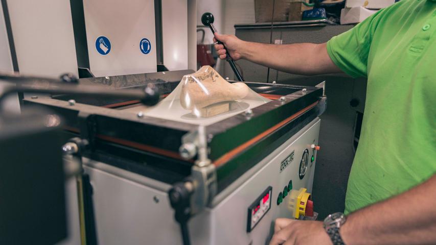Mit einer Maschine kann Ralf Mannigel einen Plastikschuh herstellen. Er legt die Holzleiste hinein, die Luft wird tiefgezogen, es entsteht ein Vakuum, und das durch die Hitze formbare Plastik stülpt sich um den Leisten.