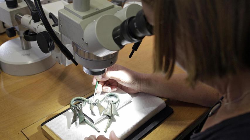 Restauratorin Ilka Weißer am Mikroskop: Sie präpariert einen seltenen Zufallsfund, einen Bronze-Aufsatz für einen Bestattungswagen aus der Zeit um 600 vor Christus, der in einem Grab bei St.Helena unweit von Nürnberg ge­funden wurde.