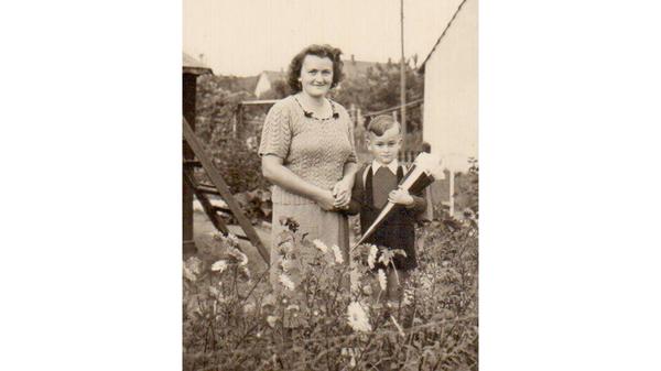 An seinem ersten Schultag im September 1950 ließ sich Manfred Schreiner an der Hand seiner Mutter im Vorgarten ihres Behelfsheimes in Buchenbühl ablichten. "Da ich mit meiner Größe nicht über die Astern schauen konnte, hat mich der Fotograf auf einen Schemel gestellt", erinnert sich Schreiner, der heute in Rückersdorf wohnt. "Vielleicht habe ich aus diesem Grunde den Merksatz für die Schulwege später im Amt so oft gebraucht: kurze Beine, kurze Wege."