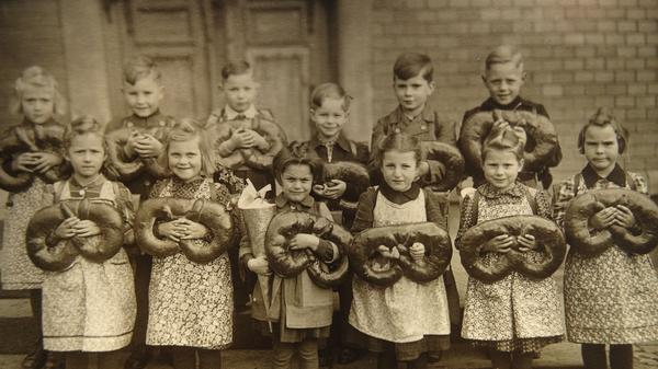Heute machen wir einfach mal etwas ganz anderes, dürfte sich der Fotograf dieses Einschulungsbildes gedacht haben. Mit unter den Brezen-Trägerinnen des Erstklassjahrgangs 1958 ist auch Roswitha Reinhard (vorne links außen).