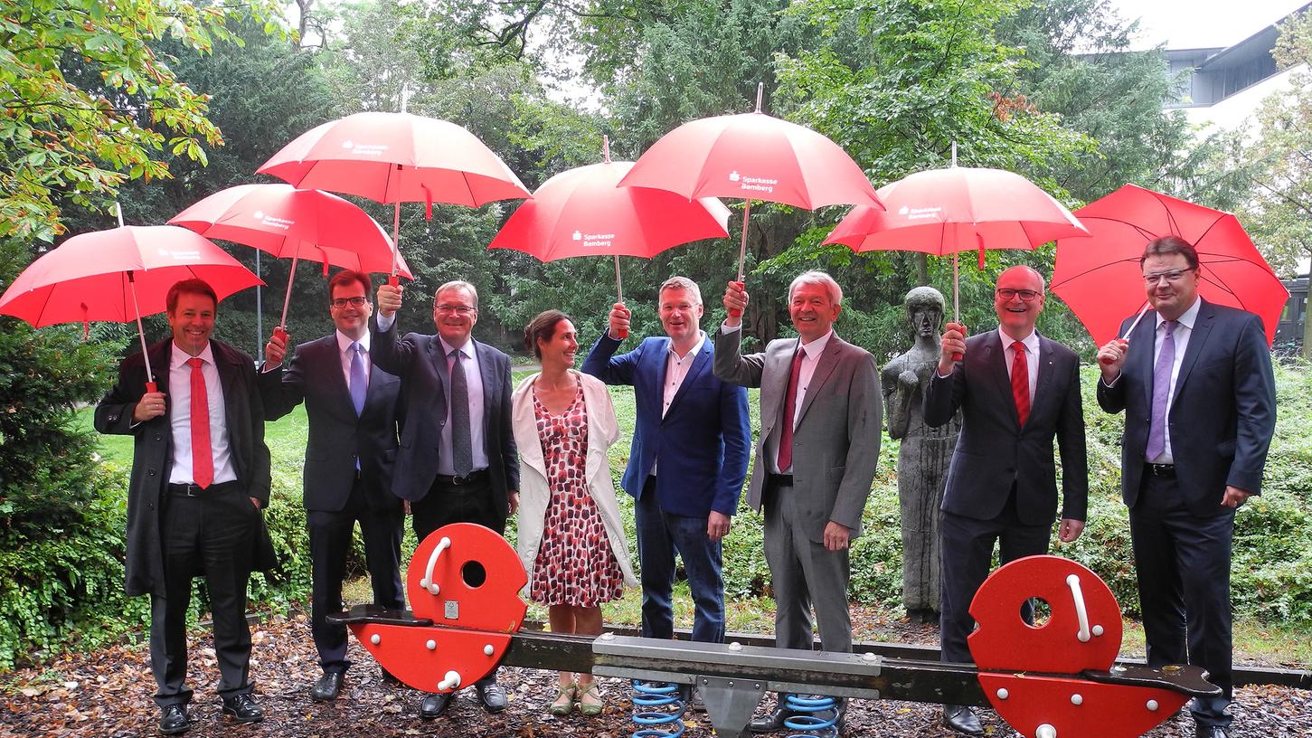 Bei Regen: Die Sparkasse hält ihre schützenden Schirme über den zu erneuernden Spielplatz im Harmoniegarten.