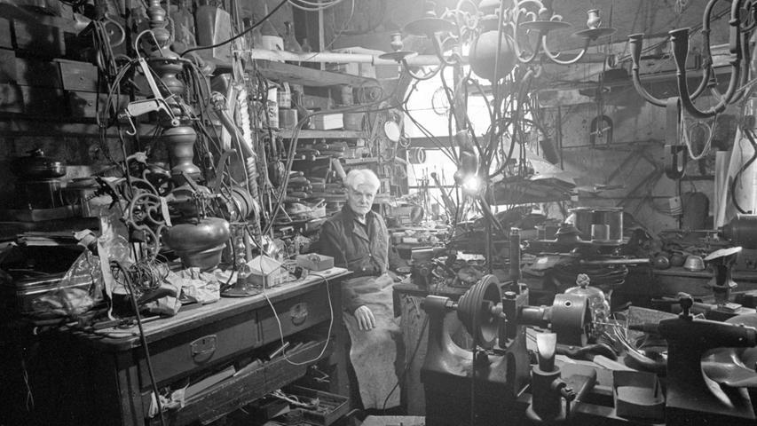 Georg Birklein in seinem Gehäuse: er sitzt inmitten einer verwirrenden Fülle von Werkzeug und Gerät.
 
  Hier geht es zum Artikel vom 11. Oktober 1966: Ein Silberschmied in seiner Welt