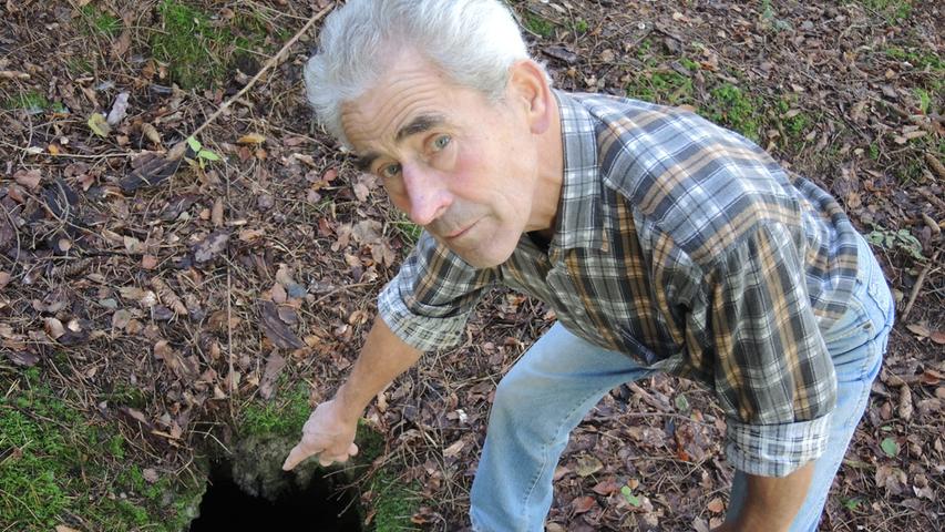 Johann Herrmann (78) zeigt auf ein Loch im Waldboden. Immer wieder entstehen Löcher im Boden rund um Rehberg - einem Karstgebiet.