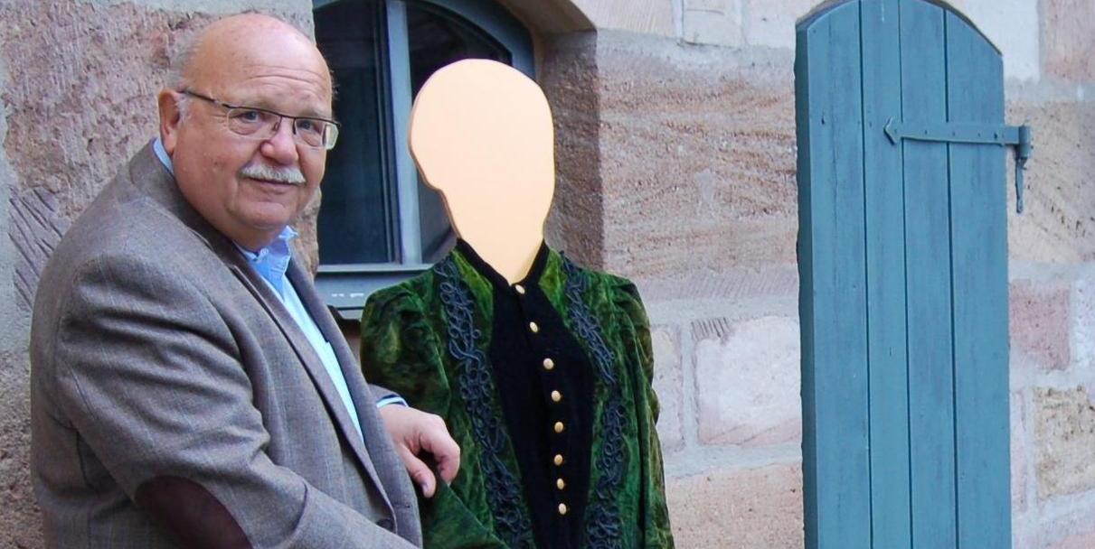 Reinhard Baumann mit einer Kleiderpuppe, die Egerländer Festtagstracht trägt.