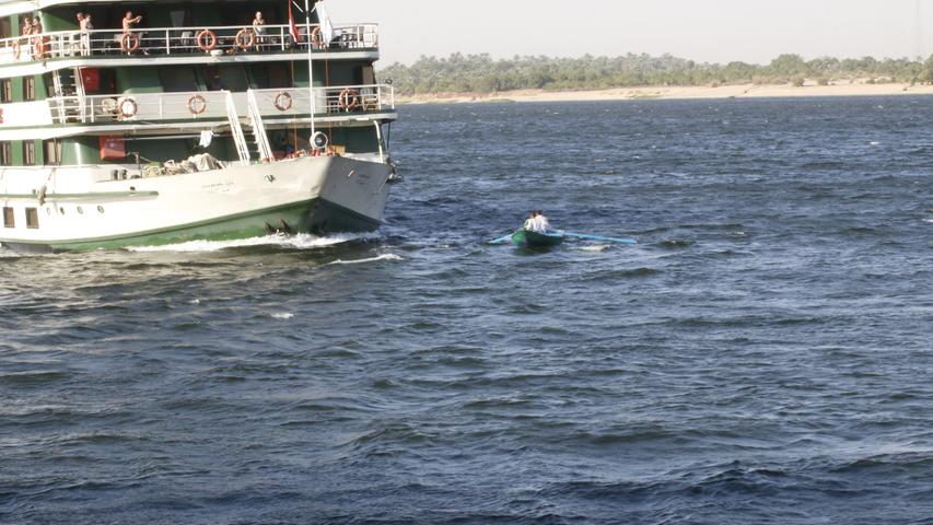 Ein Ruderboot nähert sich dem Kreuzfahrtschiff.