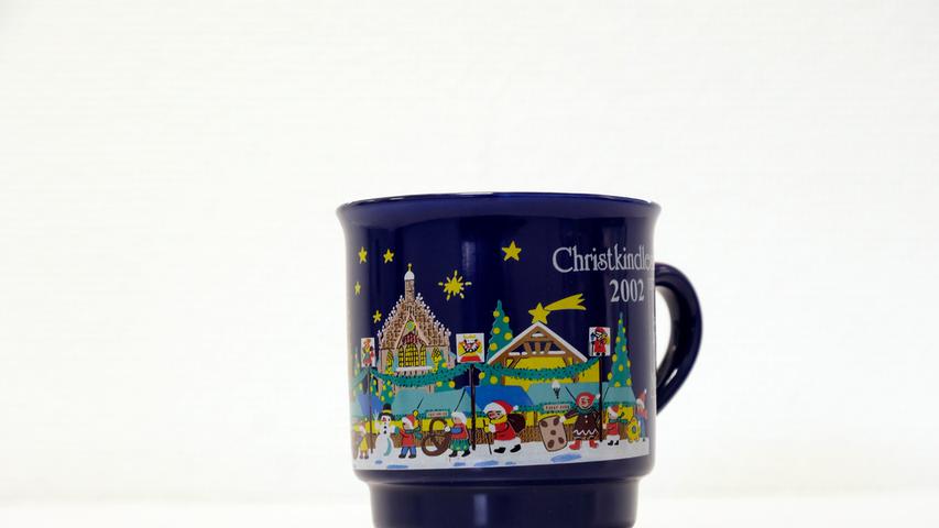 Eine dunkelblaue Tasse, gemalt mit bunten Motiven von Weihnachts- und Schneemännern über die Frauenkirche und Christkindlesmarkt-Buden gab es im Jahr 2002.