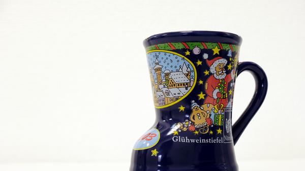 Dunkelbau, mit hellblauen Details, einem Weihnachtsmann und weiteren schön gemalten Motiven: So erschien die Tasse im Stiefel-Design im Jahr 2003. In diesem Jahr trat das Design des Glühweinstiefels zum ersten Mal auf, um etwas Neues zu kreiieren.