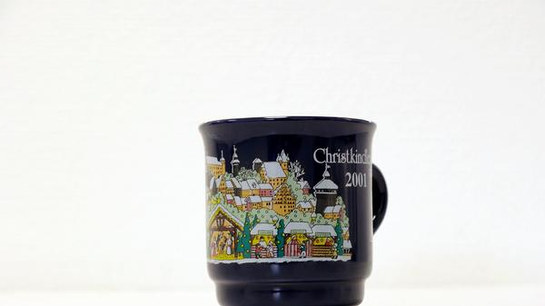 Im Vorjahr zierten die Tasse weniger Farben. Auf einer ebenfalls dunkelblauen Tasse waren etwas mehr Buden, die Burg und viele andere Gebäude zu sehen. Auch eine Krippe war auf der Tasse abgebildet.