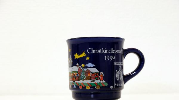 Auf einer dunkelblauen Tasse aus dem Jahr 1999 waren neben vielen schneebedeckten Buden die Frauenkirche sowie der Schöne Brunnen in bunten Farben abgebildet. Auch kleine Sterne, eine Sternschnuppe sowie ein sichelförmiger Mond zierten die Oberfläche der Tasse. In diesem Jahr gab es die erste Kinderweihnacht auf dem Nürnberger Christkindlesmarkt.
