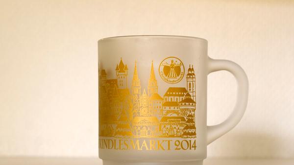 Ein Blick auf die Tasse des Jahres 2014 zeigt einen deutlichen optischen Unterschied. Anders als in den vergangenen Jahren war die Tasse milchig-glasig und mit goldenen Details geschmückt. Besonders die Architektur Nürnbergs war darauf zu sehen. So etwa die Lorenzkirche und die Kaiserburg.
