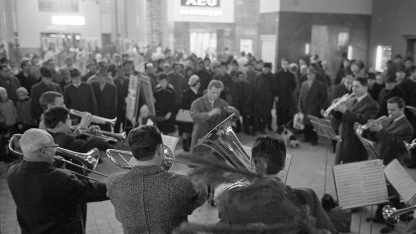 Ein Stück Weihnacht im betriebsamen Hauptbahnhof: der Wöhrder Posaunenchor spielt unter dem großen Lichterbaum; Pfarrer Heimo Liebl spricht zu Reisenden und Passanten, die sich um ihn scharen.  Hier geht es zum Artikel vom 27. Dezember 1966: Weiße Weihnacht ließ sich Zeit