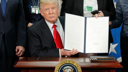 US-Präsident Donald Trump hält das unterzeichnete Dekret hoch, welches den Bau der Mauer und weitere Maßnahmen bezüglich illegaler Einwanderung beinhaltet. 
