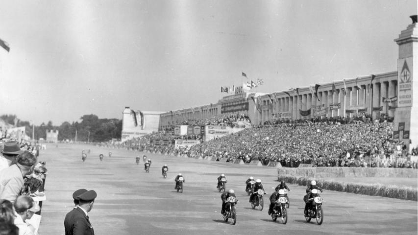 Eine bunt geschmückte und voll besetzte Steintribüne und davor rauschen die Motorräder über die Strecke: Dieses Bild stammt aus den 1950er Jahren, als der Motorsport bereits, man sieht es an den Massen an Zuschauern, eine große Rolle gespielt hat in Nürnberg.