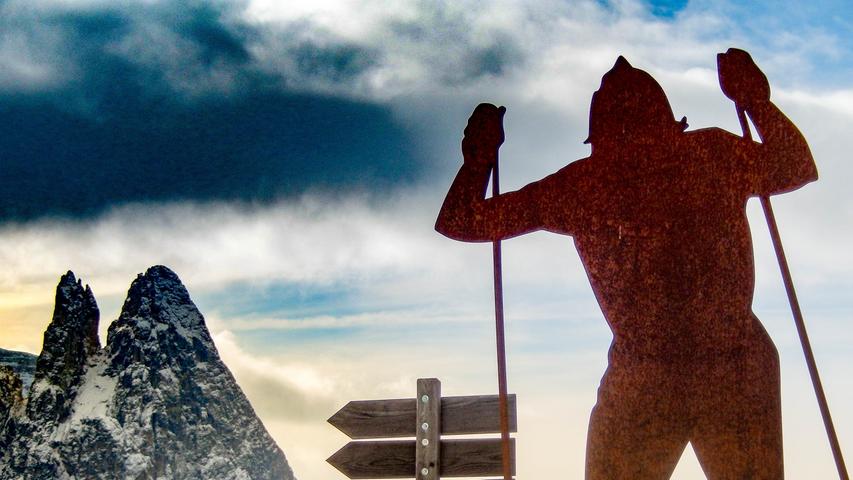 Die Silhouette eines Langläufers vor dem markanten Profil des Schlernmassives. Das Kunstwerk aus Metall ist am Nordic Ski Center an der Bergstation aufgestellt.