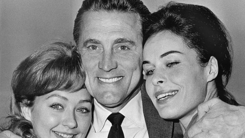Der US-amerikanische Schauspieler Kirk Douglas posiert während seines Deutschland-Besuchs 1960 in München mit den Schauspielerinnen Christine Kaufmann (links) und Barbara Rütting, den Hauptdarstellerinnen des Films "Stadt ohne Mitleid", in dem Douglas einen Militär-Verteidiger spielt.