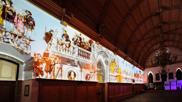 Quer durch die Kunstgattungen war Dürer tätig: Er malte und zeichnete nicht nur, sondern lieferte auch Entwürfe, die anschließend von spezialisierten Künstlern wie Wand- oder Glasmalern oder Bildhauern ausgeführt wurden. Der prestigeträchtigste Auftrag, den die Stadt Nürnberg zu Beginn der 1520er Jahre vergeben konnte, war die Leitung der künstlerischen Neuausstattung des Rathauses. Die Mammutaufgabe ging an Dürer. Das Foto zeigt die städtische Aktion, bei der die Malereien vor einigen Jahren auf die Rathauswand projiziert wurden.