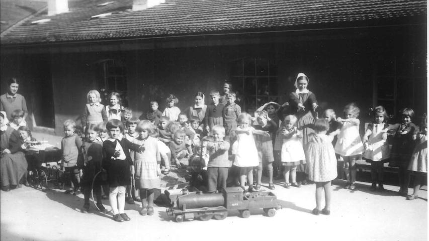 Bewegung an der frischen Luft tut gut, das wussten die Kindergärtnerinnen auch schon Anfang der 1930er Jahre. Die Kinder hätten wahrscheinlich lieber mit der tollen Lokomotive gespielt oder im Sandkasten gebuddelt, anstatt Kniebeugen zu machen.