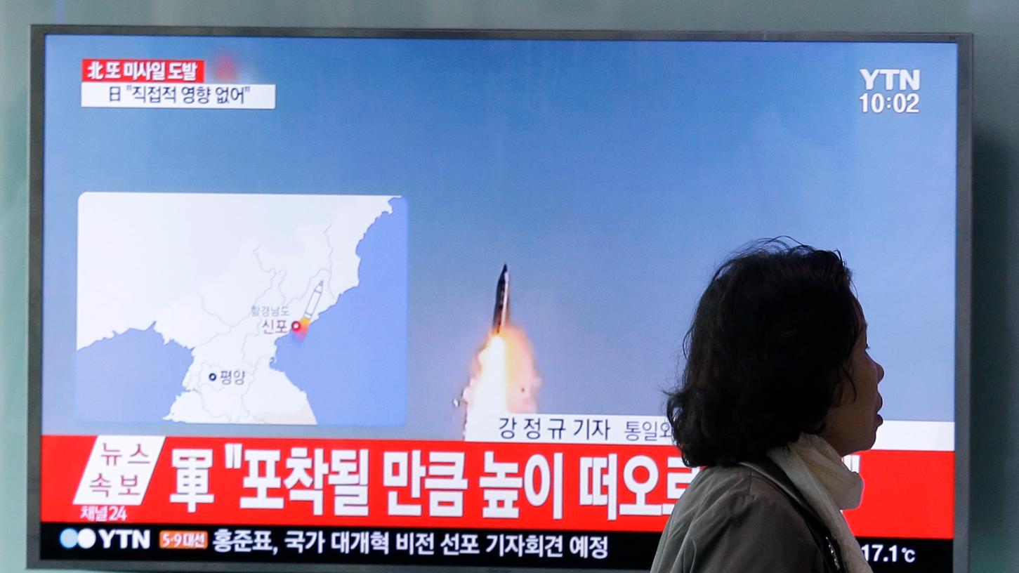 Eine Frau geht am Sonntag am Bahnhof in Seoul an einem TV-Gerät vorbei, das eine Archivfilmaufnahme von einer nordkoreanischen Rakete zeigt.