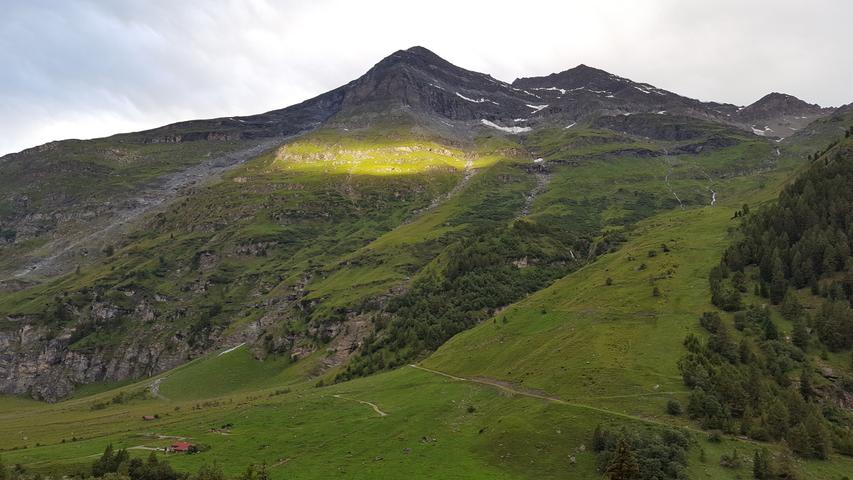 Lichtspiel: Die Sonne beleuchtet durch ein Wolkenloch hindurch den kleinen Teil eines Berghangs.