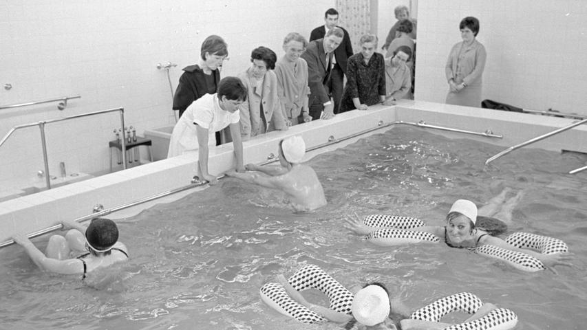Fleißig machen die Patientinnen im Bewegungsbad ihre Übungen, die einen mit Hilfe der Luftkissen, die anderen an der Haltestange. Die Bademeisterin gibt vor den Gästen Anweisungen.  Hier geht es zum Artikel vom25. April 1967: Wasser macht gesund.