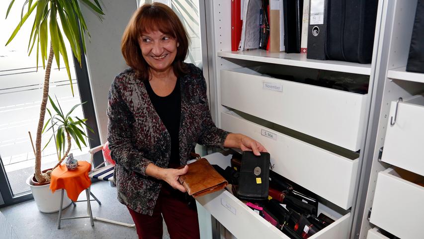 Eine Mitarbeiterin zeigt, wie viele Geldbeutel in Schubladen verstaut sind.