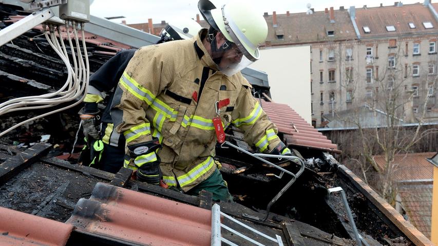 Nach einem Brand in der Waldstraße entfernen Feuerwehrmänner Balken und Schutt im ausgebrannten Dachstuhl eines Hinterhauses, um zu den letzten Glutnestern vorzustoßen.