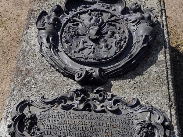 Epitaphien erzählen Zeitgeschichte, so auch am Grab von B. Viatis und A. Gutthäter, 1641. Das Medaillon zeigt die Wappen; die Inschrift lässt oben in einem Mix aus figürlichen und ornamentalen Motiven eine Maske erkennen. Ein Zeichen dafür, wie aktuell die Ornamentik in Nürnberg aufgegriffen wurde.