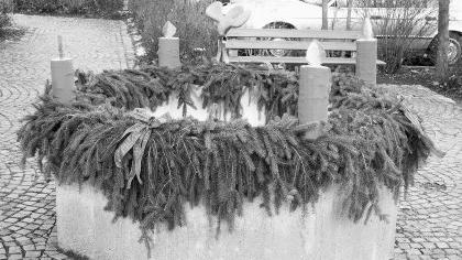 DIETERSDORF - Der Adventskranz gehört in fast jeder Familie zur Adventszeit. In Dietersdorf ist in diesem Jahr erstmals am Rosa-Mihalka-Platz auf dem Brunnen ein ganz besonderer Adventskranz angebracht. Der Brunnenrand wurde liebevoll mit Zweigen und roten Schleifen dekoriert. Und darauf angebracht sind vier Kerzen, aus Holz geschnitzt. Dieses Kunstwerk wurde nicht für viel Geld von einem Künstler erworben. Spontan und ohne viel Aufhebens hat sich Udo Haußmann zusammen mit seiner Ehefrau Petra Haußmann, Vorsitzende des Obst- und Gartenbauvereins, ans Werk gemacht und diese Idee umgesetzt. Ohne die Stadtkasse zu belasten, werden in dem Schwabacher Ortsteil durch Eigeninitiative immer wieder Akzente gesetzt. Ebenso erstrahlt jährlich auf Initiative der Feuerwehr am Feuerwehrhaus ein Christbaum, der zur Weihnachtsfeier der Wehrleute einlädt. – Unser Bild zeigt den geschmückten Brunnen. DIETERSDORF - Der Adventskranz gehört in fast jeder Familie zur Adventszeit. In Dietersdorf ist in diesem Jahr erstmals am Rosa-Mihalka-Platz auf dem Brunnen ein ganz besonderer Adventskranz angebracht. Der Brunnenrand wurde liebevoll mit Zweigen und roten Schleifen dekoriert. Und darauf angebracht sind vier Kerzen, aus Holz geschnitzt. Dieses Kunstwerk wurde nicht für viel Geld von einem Künstler erworben. Spontan und ohne viel Aufhebens hat sich Udo Haußmann zusammen mit seiner Ehefrau Petra Haußmann, Vorsitzende des Obst- und Gartenbauvereins, ans Werk gemacht und diese Idee umgesetzt. Ohne die Stadtkasse zu belasten, werden in dem Schwabacher Ortsteil durch Eigeninitiative immer wieder Akzente gesetzt. Ebenso erstrahlt jährlich auf Initiative der Feuerwehr am Feuerwehrhaus ein Christbaum, der zur Weihnachtsfeier der Wehrleute einlädt. – Unser Bild zeigt den geschmückten Brunnen.