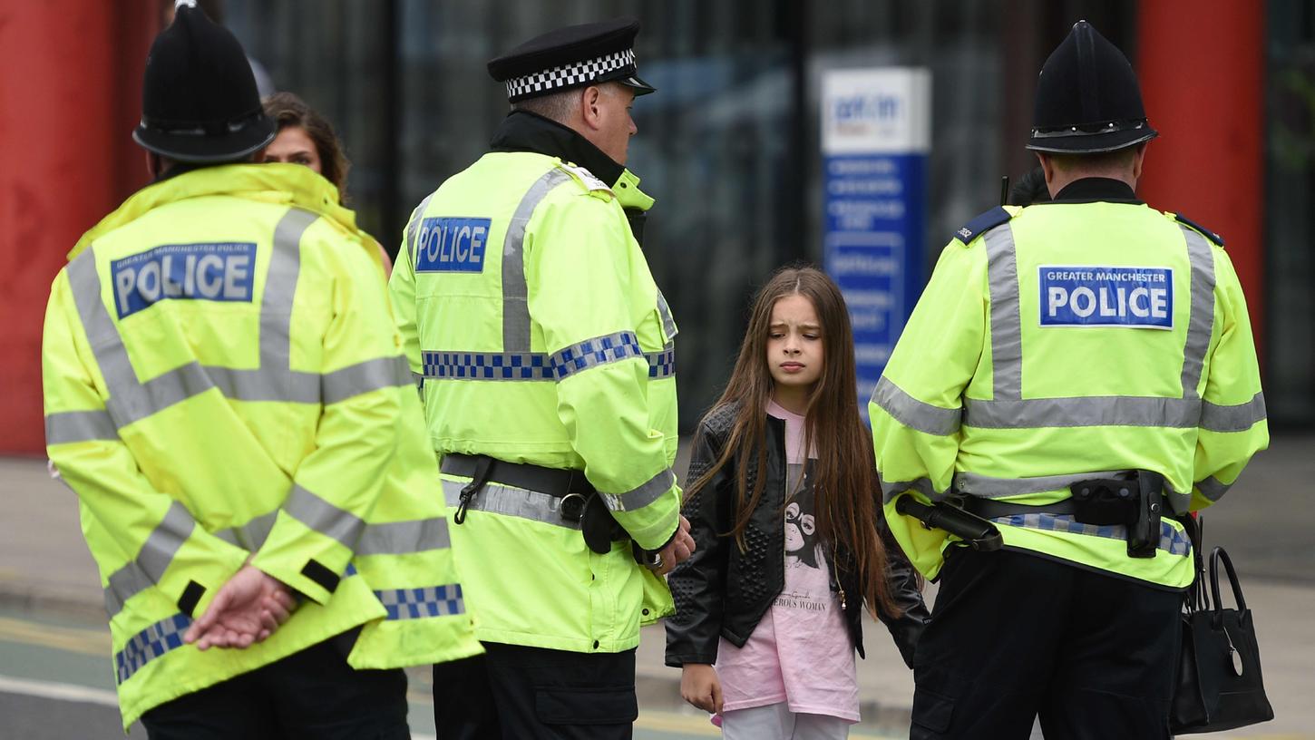 Ein Mädchen steht vor Polizisten in Manchester: Stunden vorher waren hier Dutzende Menschen umgekommen.