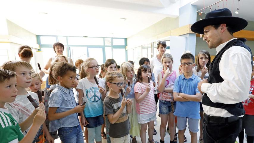 Lukas Wunner erklärt den Kindern die Handwerkstracht. Derweil schlecken die Schüler ein Eis, das ihnen zum Richtfest spendiert wurde.