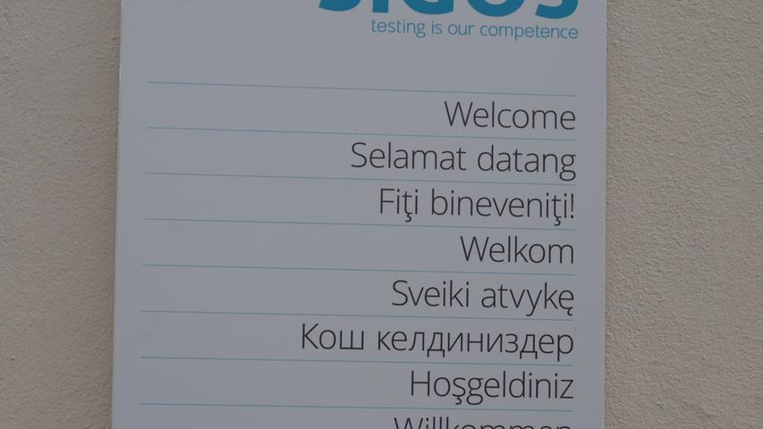 Ein Mieter von Anfang an ist die Firma Sigos, die sich mehrfach vergrößert hat. Dieses Firmenschild verkündet "Testing is our Competence" - und das Willkommen der in 150 Ländern tätigen Firma ist auf allen Schildern in acht Sprachen verfasst.