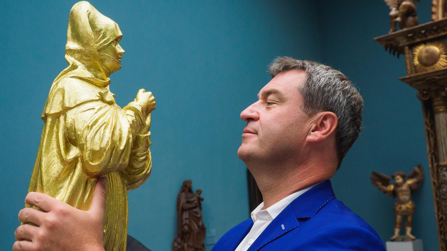 Der Bayerische Finanzminister Markus Söder (CSU) hält eine goldfarbene Madonna-Figur in den Händen.