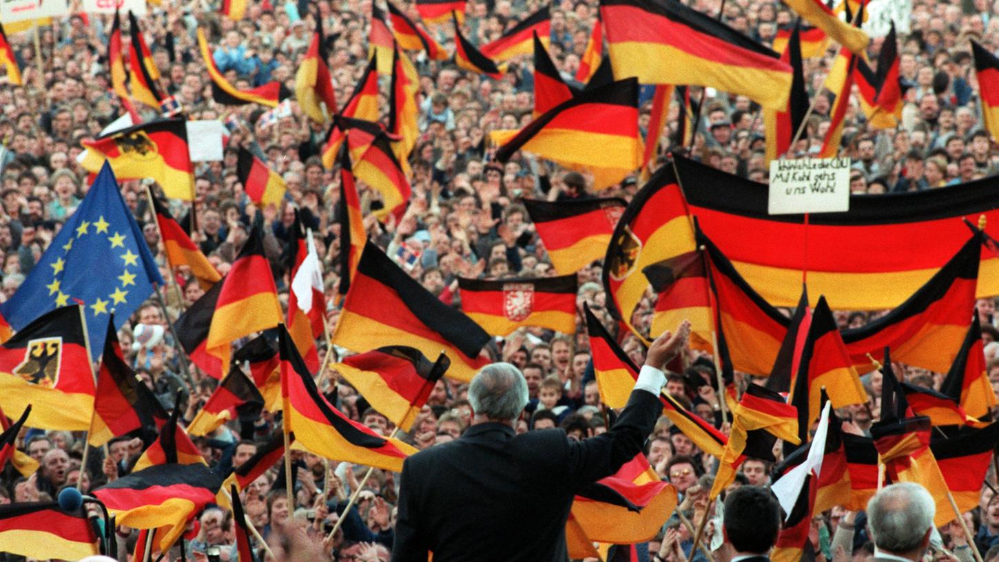 Eine historische Gelegenheit und ein Meer von Fahnen: Helmut Kohl winkt 1990 bei einer Wahlkampfveranstaltung in Erfurt den begeisterten Menschen zu. Die Bürger wollten die deutsche Einheit — und sie wollten Kohl als Kanzler.