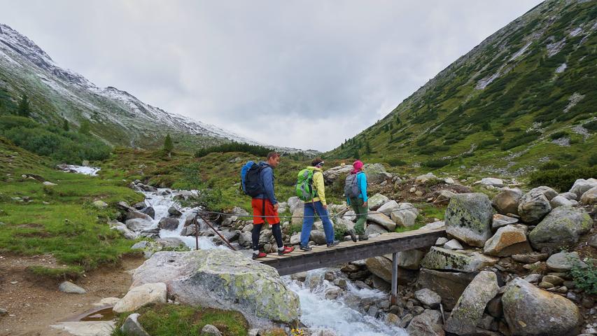 Fast bis auf 2000 Meter begleitet die Alpenüberquerer auf der Königsetappe über den den Alpenhauptkamm der Bach im Zamser Grund.