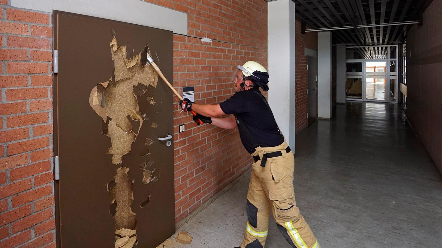 Ein Feuerwehrmann schlägt die Tür eines Klassenzimmers ein.