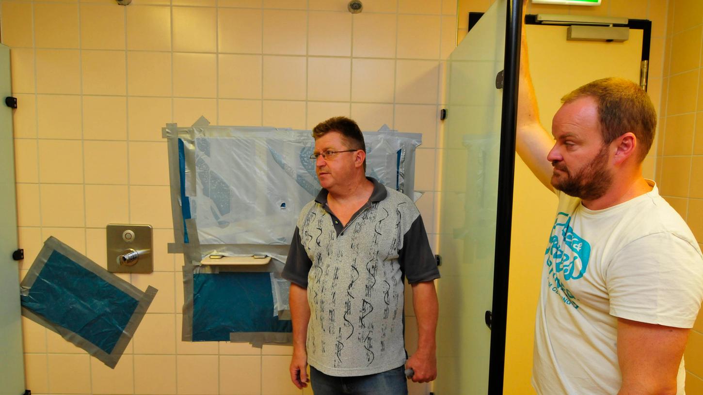 Jörg Mann (li.) und Christian Lenkl vom Königsbad zeigen die notdürftig kaschierten Mängel in einer Dusche.