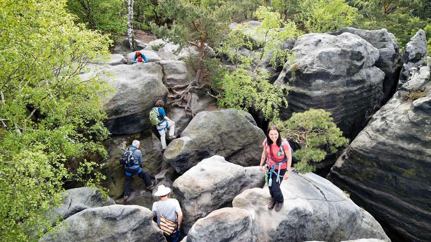 Führerin Alrun Flechsig (vorne) und ihre Wandergruppe im Felsenlabyrinth, das immer wieder überraschende Kletterpassagen und Ausblicke bietet.