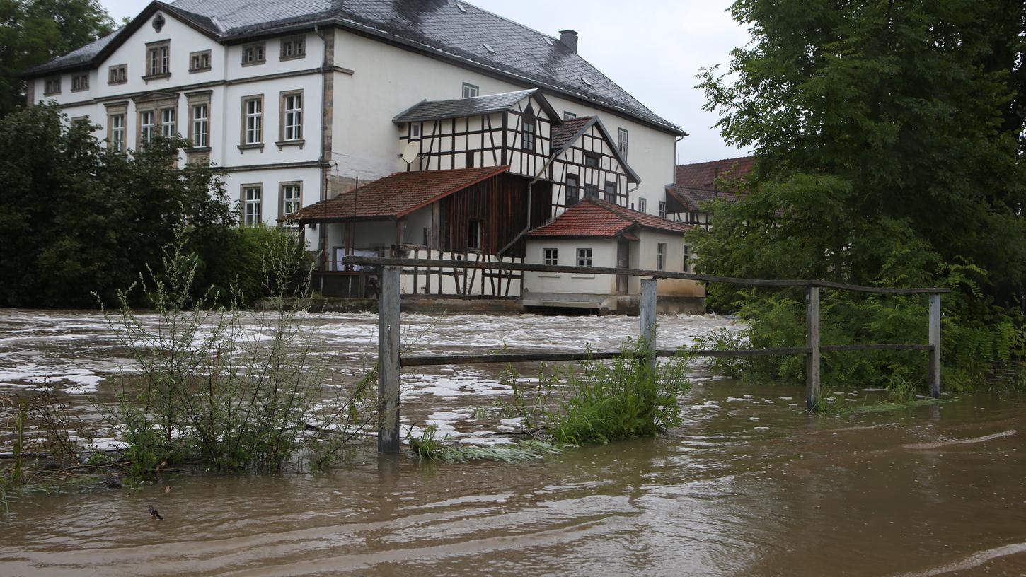 In Schenkenau im Landkreis Coburg ist die Itz über die Ufer getreten und walzt sich als braune Schlammlawine durch die Straßen.