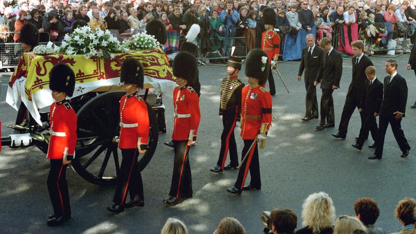 Männer der Garde eskortieren Dianas Sarg unter riesiger Anteilnahme der Bevölkerung. Hinterdrein folgen ihre Söhne William und Harry, ihr Exmann Prinz Charles, dessen Vater Prinz Philip und Dianas Bruder Charles. Auf dem Sarg liegt ein an "Mummy" adressierter Brief, ein letzter Abschiedsgruß.