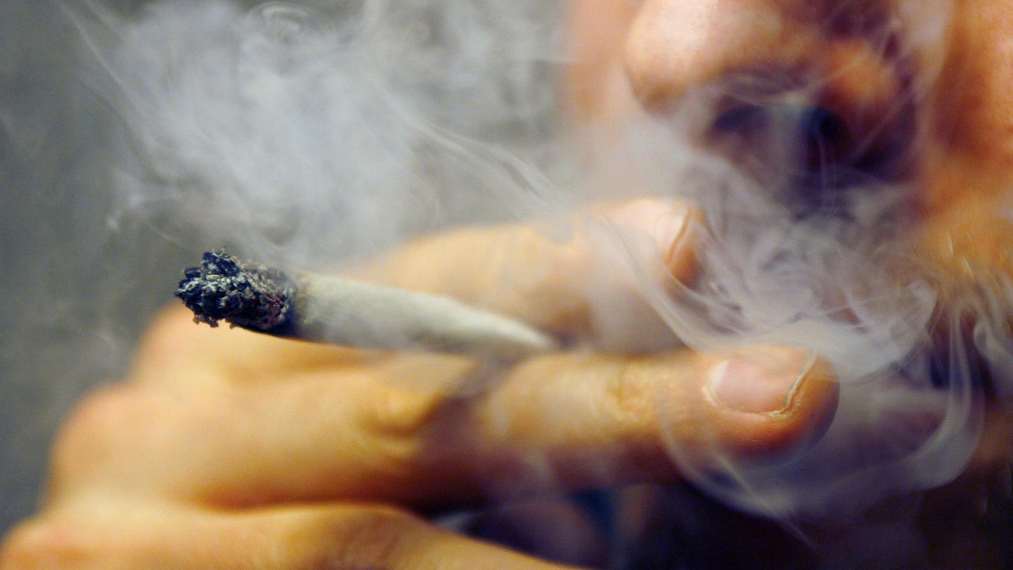Ein Mann raucht einen Joint mit Marihuana (Symbolbild)
