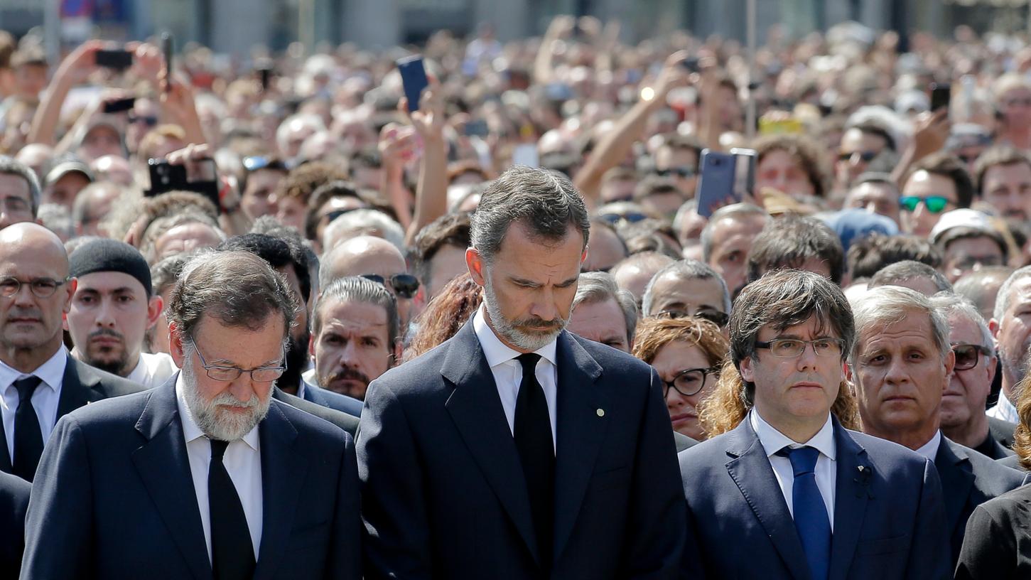 König Felipe VI. (M), Ministerpräsident Mariano Rajoy (l) und der katalanische Regierungschef Carles Puigdemont (r) gedenken in einer Schweigeminute der Opfer des Terroranschlags auf Flaniermeile Las Ramblas in Barcelona.