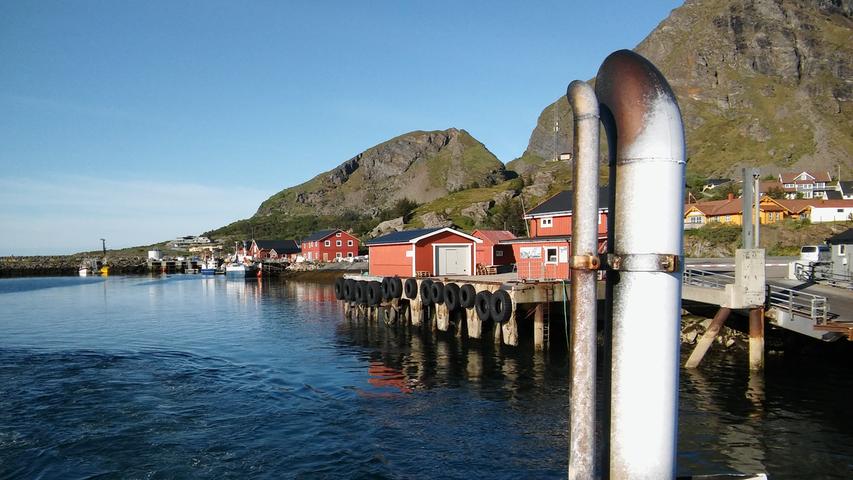Typisch skandinavisch-rote Hagerschuppen stehen in dem Hafen.