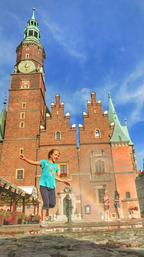 Kinder haben ihren Spaß an einer Wasserdüse vor dem Rathaus von Breslau.