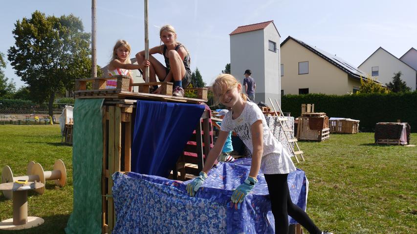 Mit viel blauem Stoff haben Lisa, Nele und Lina (von links) ihre Holzhütte geschmückt. "Das soll ans Meer erinnern", erzählt Lina. Die beiden anderen bringen gerade einen Fahnenmast auf dem Dach an.
