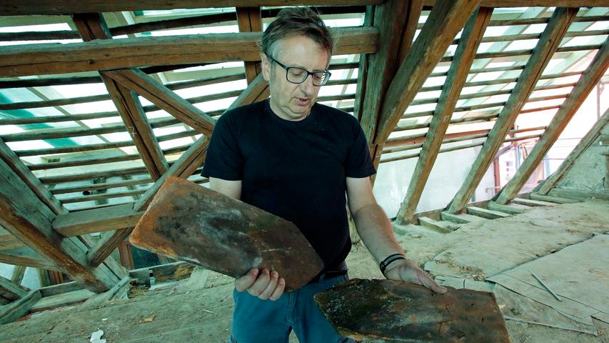 Architekt Georg Leyh zeigt alte Ziegel, die auf dem Dach gefunden wurden.