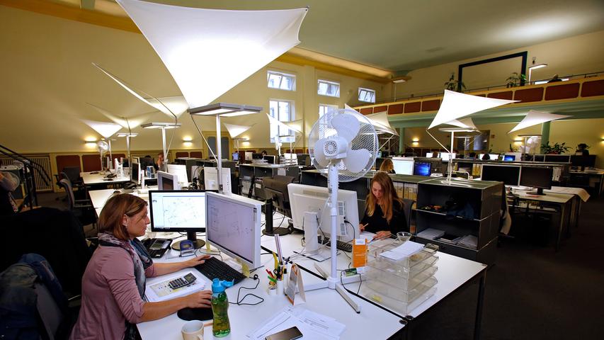 Wie weiße Segel schweben die Schreibtischlampen über dem Arbeitsbereich im großen Saal.